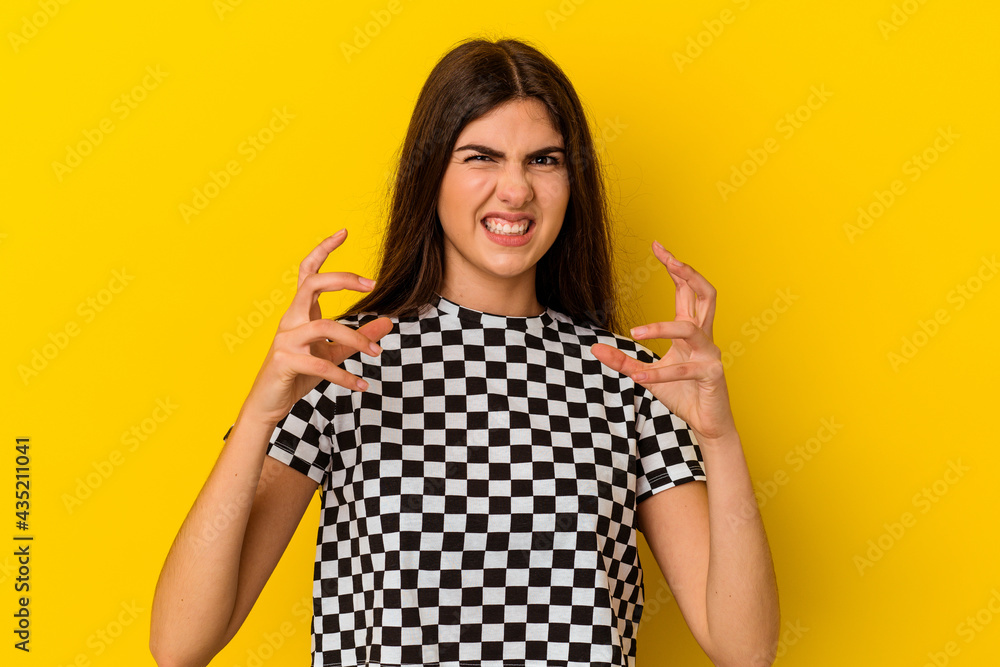 Young caucasian woman isolated on yellow background upset screaming with tense hands. Young caucasian woman isolated on yellow background upset screaming with tense hands.