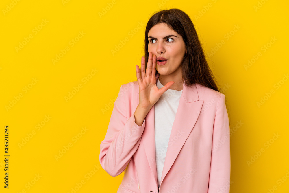 Young caucasian woman isolated on yellow background is saying a secret hot braking news and looking aside Young caucasian woman isolated on yellow background is saying a secret hot braking news and looking aside