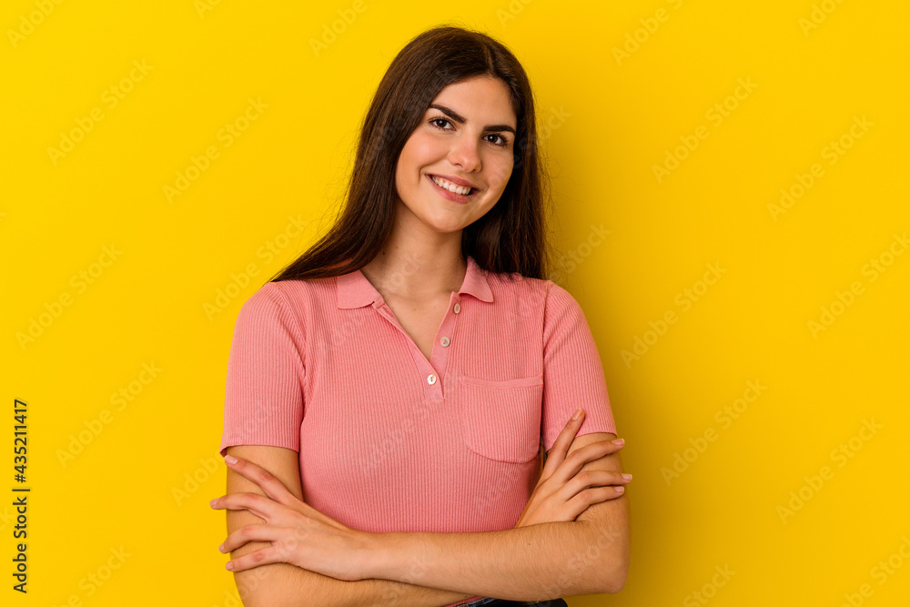 Fototapeta premium Young caucasian woman isolated on yellow background who feels confident, crossing arms with determination.