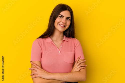 Young caucasian woman isolated on yellow background who feels confident, crossing arms with determination.