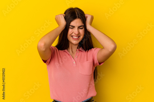 Young caucasian woman isolated on yellow background covering ears with hands.
