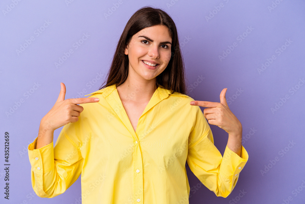 Young caucasian woman isolated on purple background points down with fingers, positive feeling. Young caucasian woman isolated on purple background points down with fingers, positive feeling.