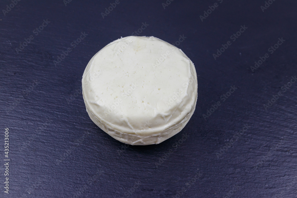 Soft Adyghe cheese on black slate background Soft Adyghe cheese on black slate background