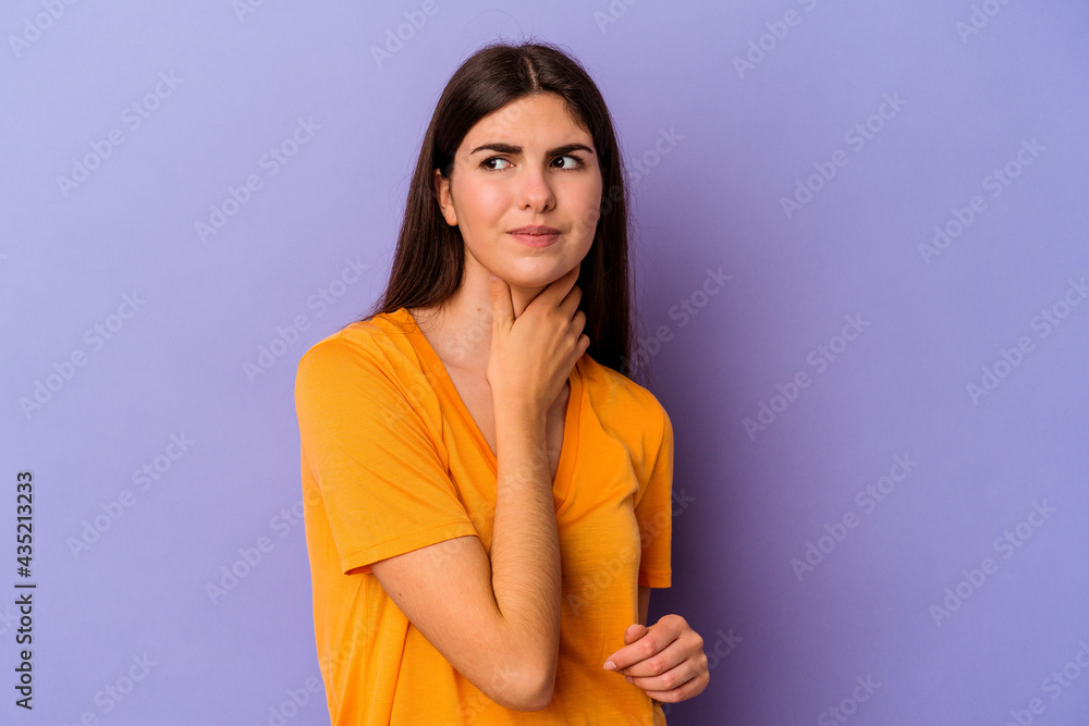 Obraz premium Young caucasian woman isolated on purple background suffers pain in throat due a virus or infection.
