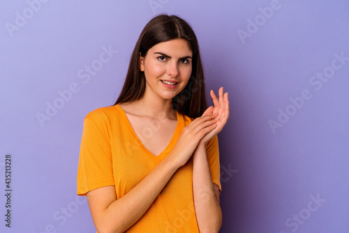 Young caucasian woman isolated on purple background feeling energetic and comfortable, rubbing hands confident.