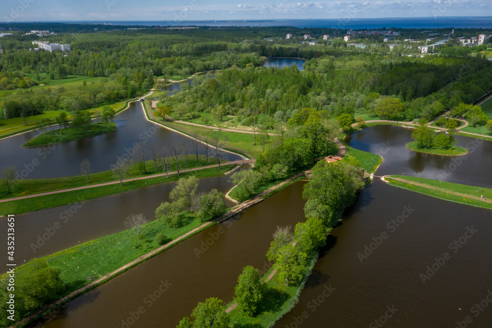 Fototapeta premium A panoramic view from a height of the ponds and the Landscape Park in Peterhof, the meadow garden, walking paths, the destroyed pavilion.