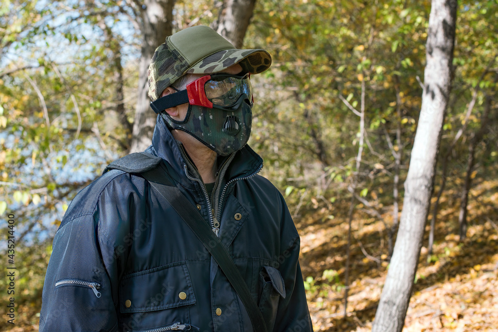 A man wearing a respirator mask and protective glasses in the forest at COVID-19 period.