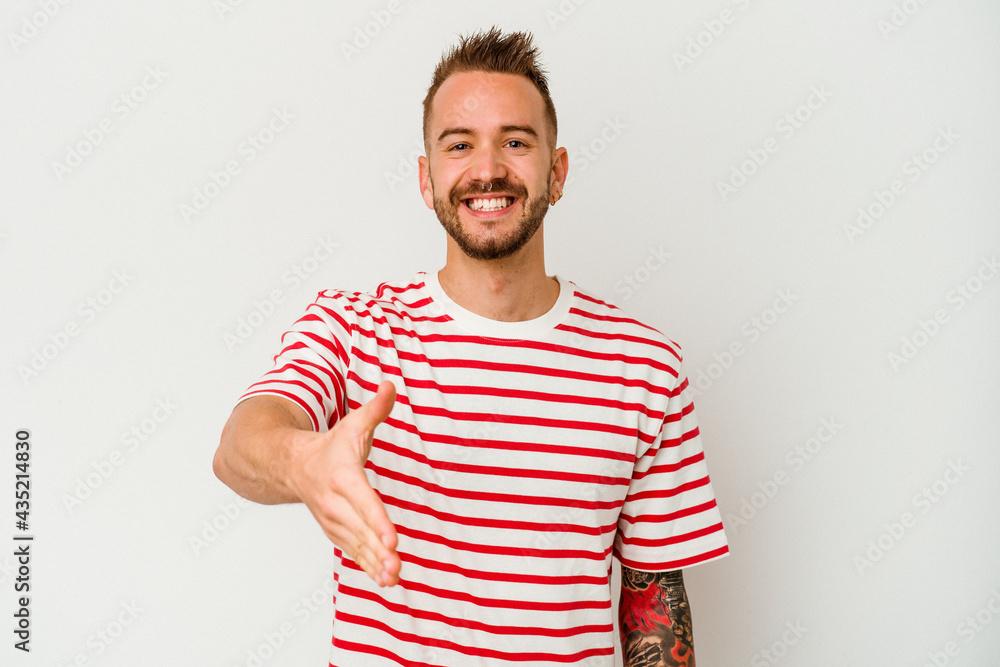 Young tattooed caucasian man isolated on white background stretching hand at camera in greeting gesture. Young tattooed caucasian man isolated on white background stretching hand at camera in greeting gesture.