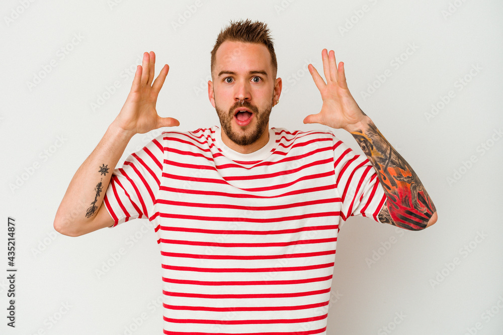 Naklejka premium Young tattooed caucasian man isolated on white background celebrating a victory or success, he is surprised and shocked.