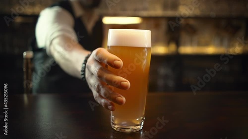 Bartender serving customers in pub, puts pint of beer. Mug of unfiltered beer. photo