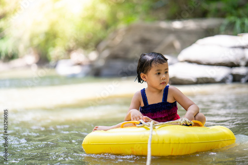 Little  girl sitting in inflatable tube against streams background. © tienuskin