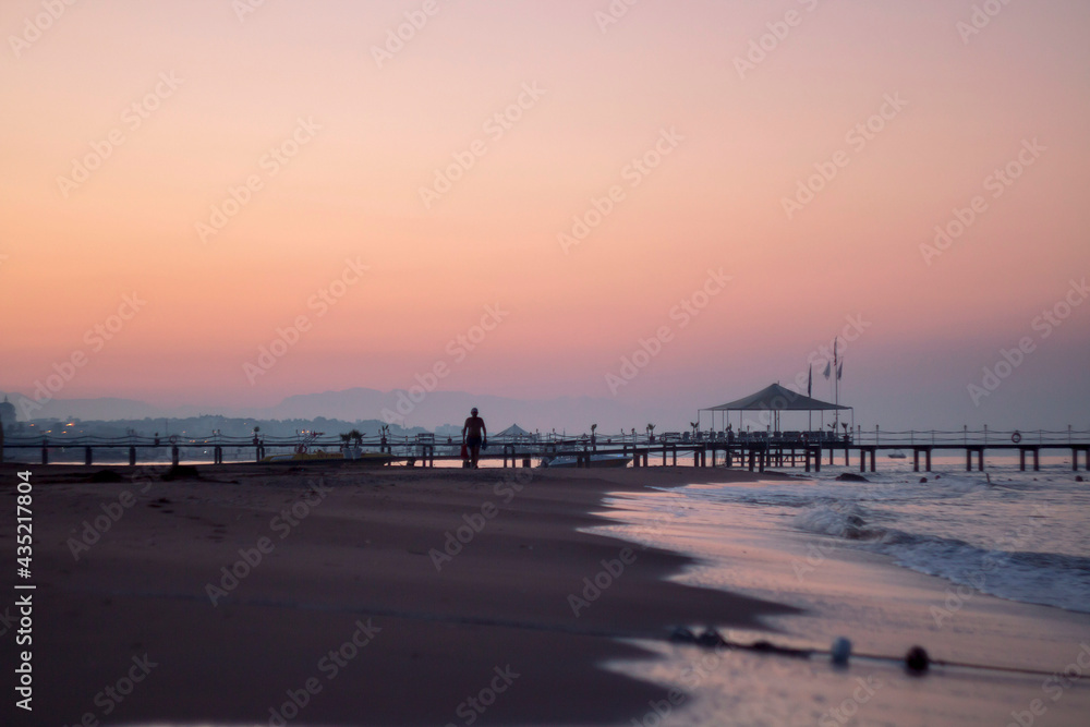 Silhouettes on a beach of Mediterranean sea at sunrise on summer morning