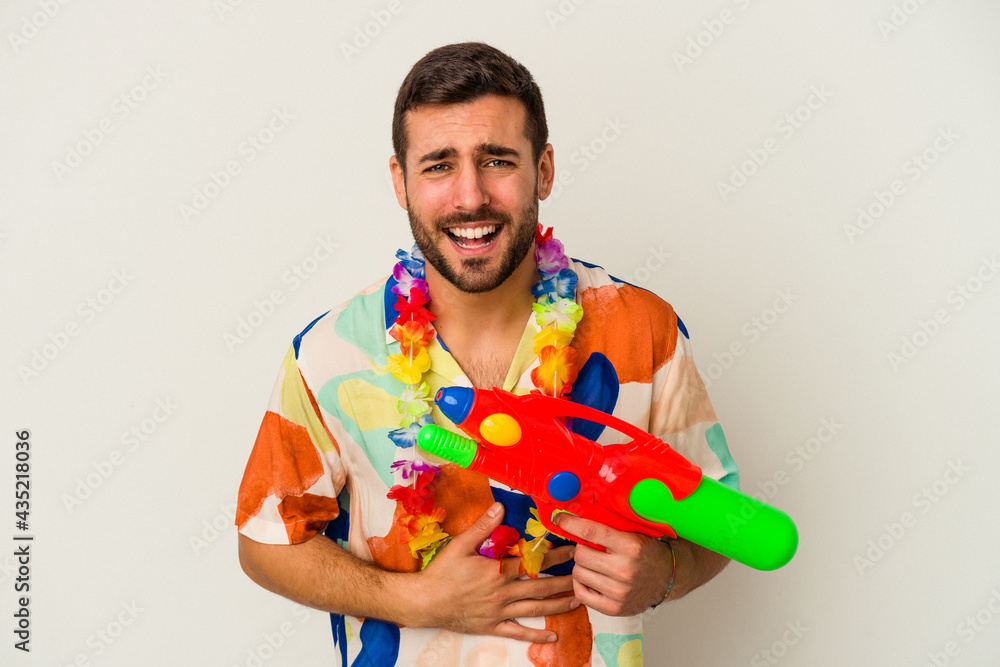 Young caucasian woman on a hawaiian party holding a water gun isolated on white background laughing and having fun. Young caucasian woman on a hawaiian party holding a water gun isolated on white background laughing and having fun.