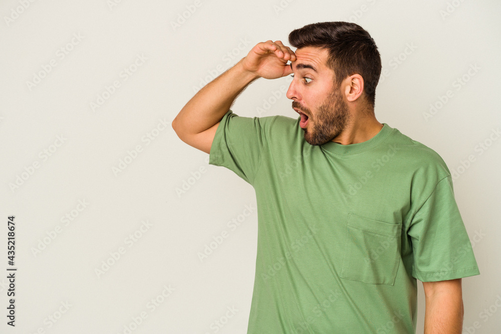 Obraz premium Young caucasian man isolated on white background looking far away keeping hand on forehead.