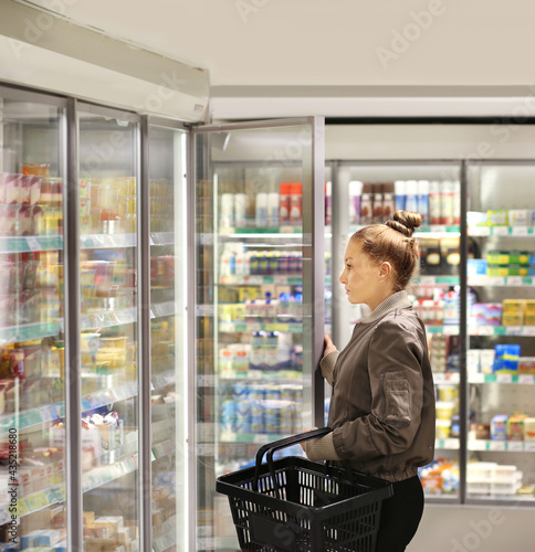 Woman choosing frozen food from a supermarket freezer