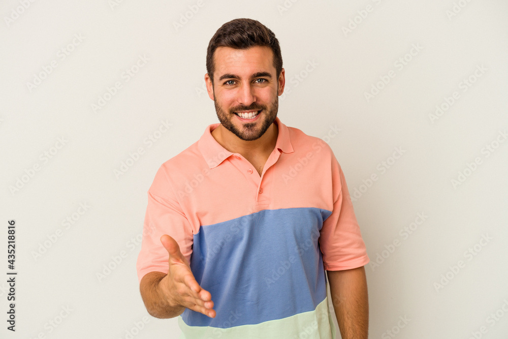 Young caucasian man isolated on white background stretching hand at camera in greeting gesture. Young caucasian man isolated on white background stretching hand at camera in greeting gesture.