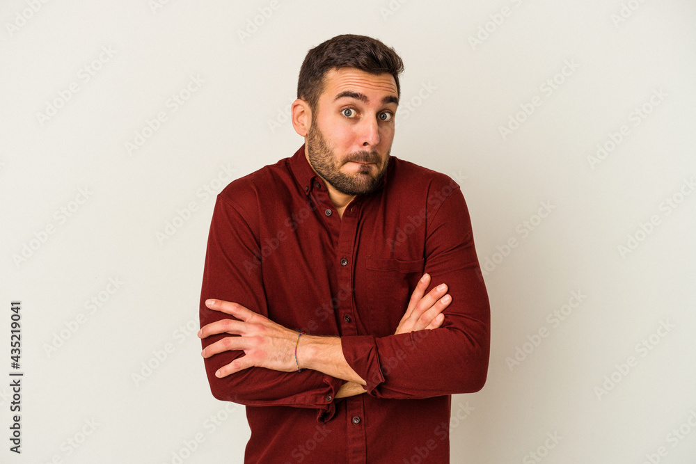 Young caucasian man isolated on white background shrugs shoulders and open eyes confused. Young caucasian man isolated on white background shrugs shoulders and open eyes confused.