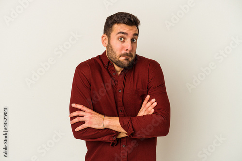 Young caucasian man isolated on white background shrugs shoulders and open eyes confused.
