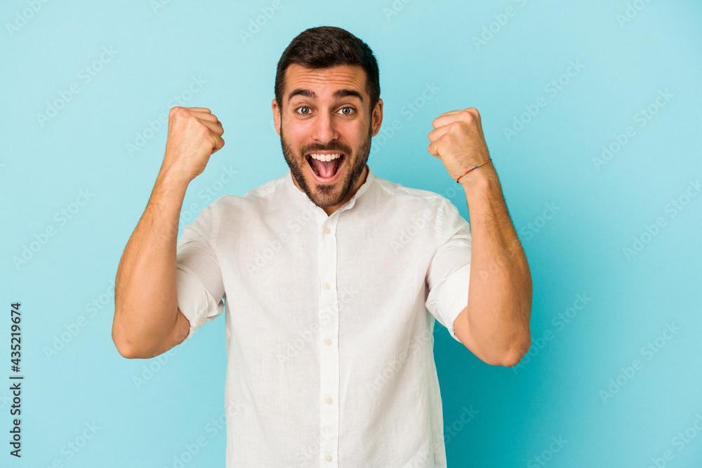Fototapeta premium Young caucasian man isolated on blue background cheering carefree and excited. Victory concept.