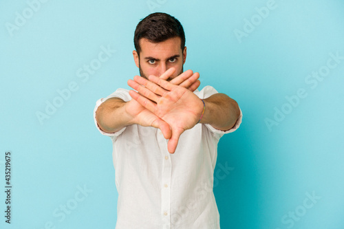 Young caucasian man isolated on blue background doing a denial gesture