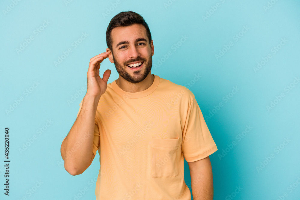 Young caucasian man isolated on blue background laughing about something, covering mouth with hands. Young caucasian man isolated on blue background laughing about something, covering mouth with hands.