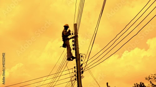 An electrician working at a newly installed utility pole - connects a new power line.