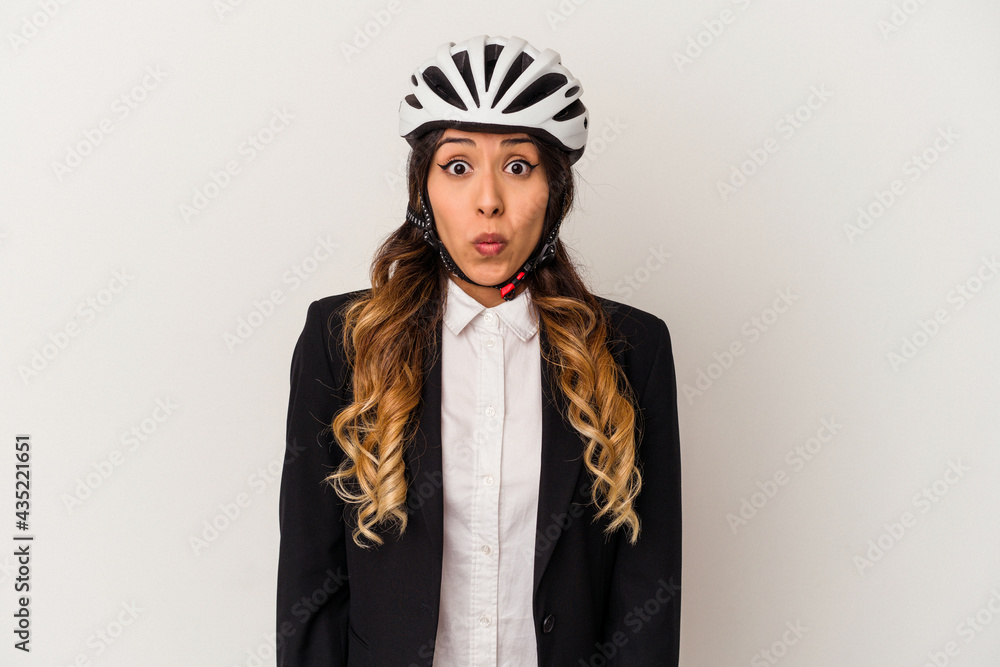Young mexican woman riding a bicycle to work isolated on white background shrugs shoulders and open eyes confused. Young mexican woman riding a bicycle to work isolated on white background shrugs shoulders and open eyes confused.