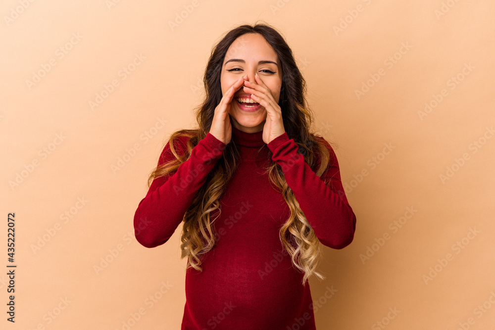 Young mexican pregnant woman isolated on beige background shouting excited to front. Young mexican pregnant woman isolated on beige background shouting excited to front.