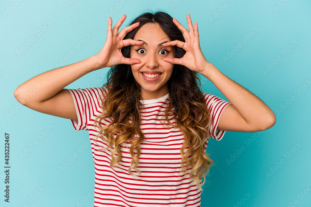 Young mexican woman isolated on blue background keeping eyes opened to find a success opportunity. Young mexican woman isolated on blue background keeping eyes opened to find a success opportunity.