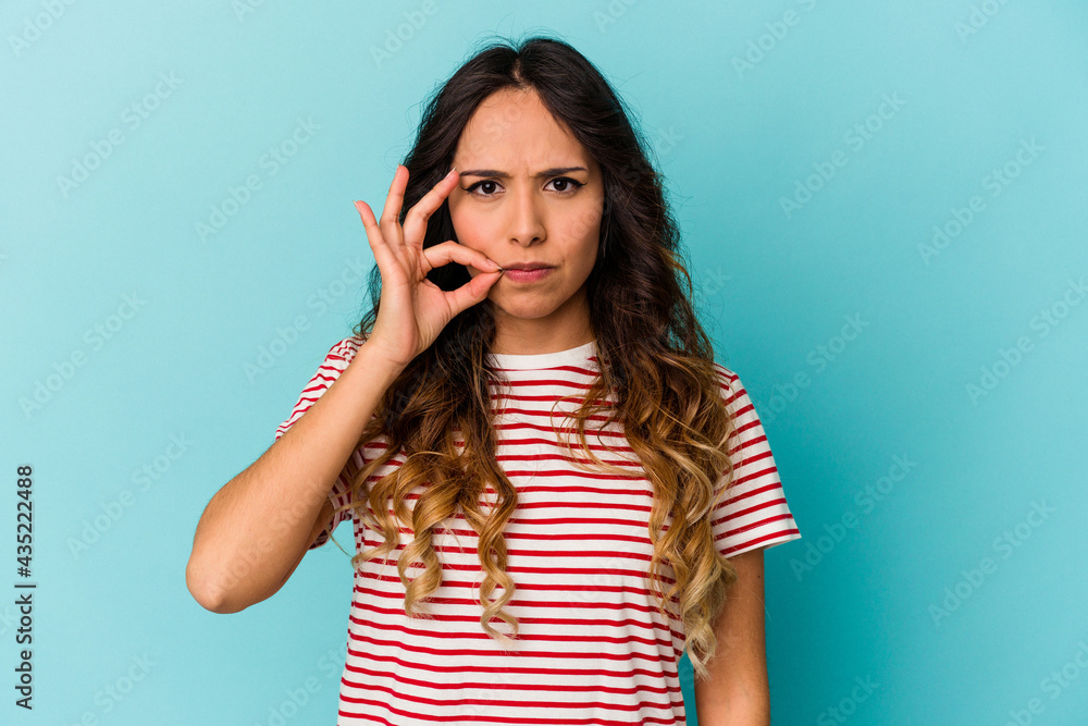 Young mexican woman isolated on blue background with fingers on lips keeping a secret. Young mexican woman isolated on blue background with fingers on lips keeping a secret.