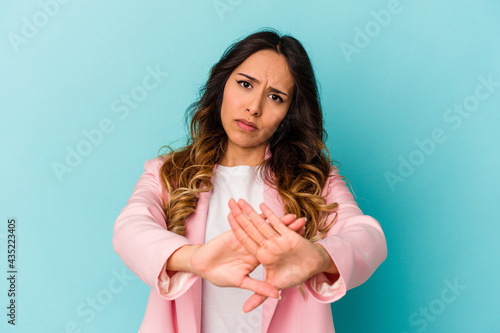 Young mexican woman isolated on blue background doing a denial gesture