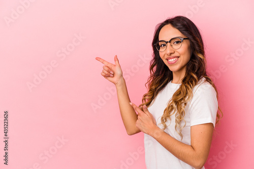 Young mexican woman isolated on pink background excited pointing with forefingers away.