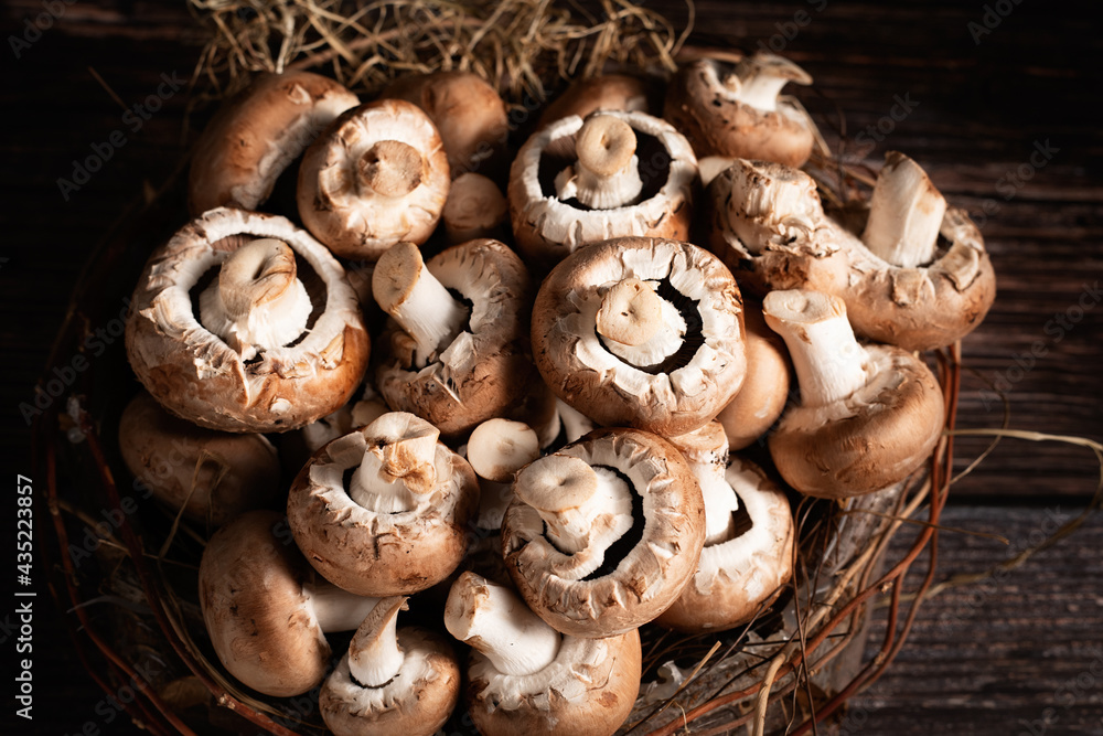 Hintergrund aus braunen Champignons, rund um zu liegt Stroh. Pilze liegen im Holzkorb. Gesundes Essen aus dem Wald. Rohes Essen, Zutat. Hintergrund aus braunen Champignons, rund um zu liegt Stroh. Pilze liegen im Holzkorb. Gesundes Essen aus dem Wald. Rohes Essen, Zutat.