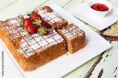 Square Raspberry and yoghurt cake with cut slice on white plate