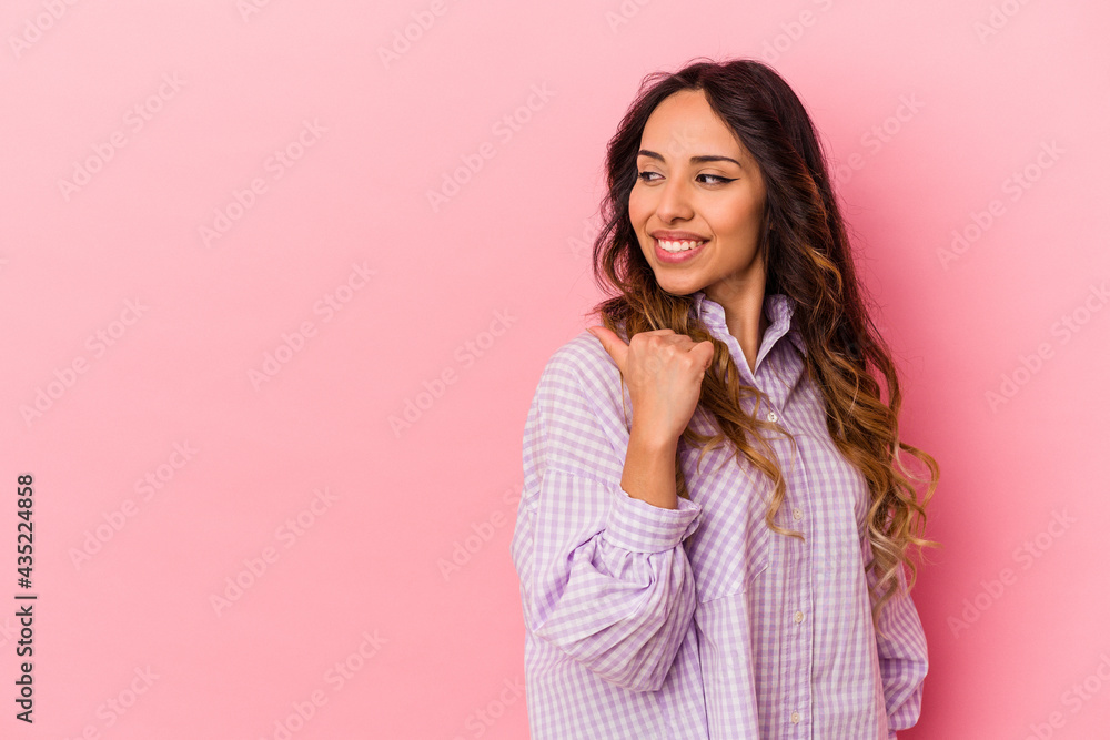 Young mexican woman isolated on pink background points with thumb finger away, laughing and carefree. Young mexican woman isolated on pink background points with thumb finger away, laughing and carefree.