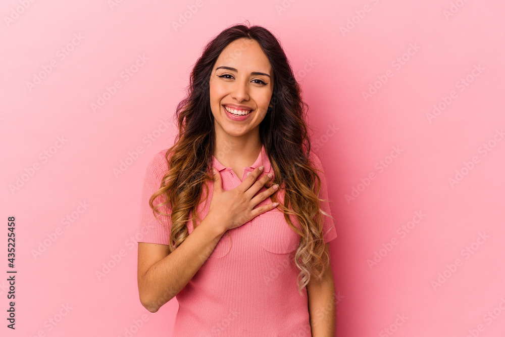 Young mexican woman isolated on pink background laughs out loudly keeping hand on chest.