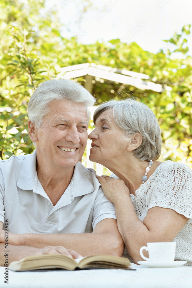 Beautiful old couple reading book at table in summer Beautiful old couple reading book at table in summer