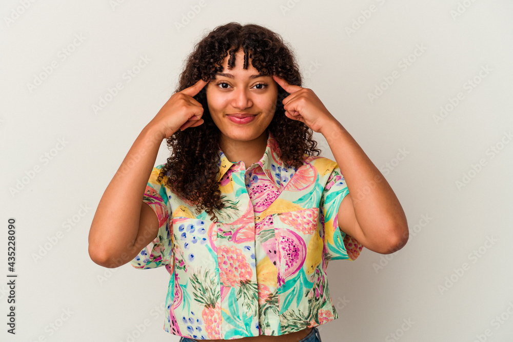 Young mixed race woman isolated on white background focused on a task, keeping forefingers pointing head. Young mixed race woman isolated on white background focused on a task, keeping forefingers pointing head.