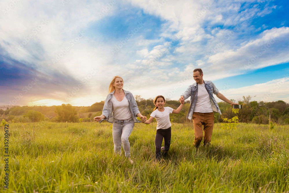 Happy family in the park evening light. The lights of a sun. Mom, dad and baby happy walk at sunset. The concept of a happy family Happy family in the park evening light. The lights of a sun. Mom, dad and baby happy walk at sunset. The concept of a happy family