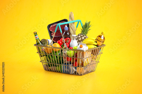 Fotografie Shopping basket full of variety of grocery products, food and drink on yellow background