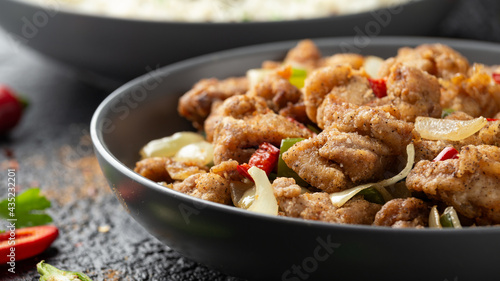 Stir fry chinese salt and pepper chicken with rice in grey bowl