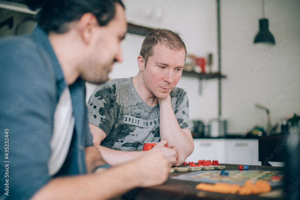 Friends play a board game in the living room Friends play a board game in the living room