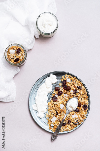 Granola with chia seeds, coconut, dry berries and yogurt in bowls on grey background, copy space. Concept of healthy breakfast menu 