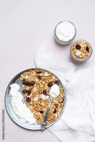 Granola with chia seeds, coconut, dry berries and yogurt in bowls on grey background, copy space. Concept of healthy breakfast menu 