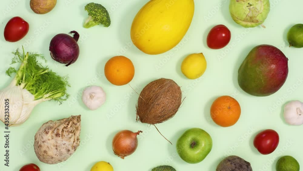 Creative pattern made of fruits and vegetables appear on light green background. Stop motion Creative pattern made of fruits and vegetables appear on light green background. Stop motion