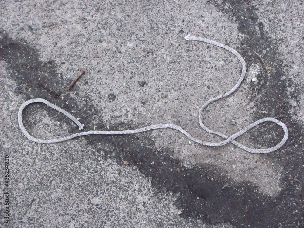 a shabby rope lying on the pavement