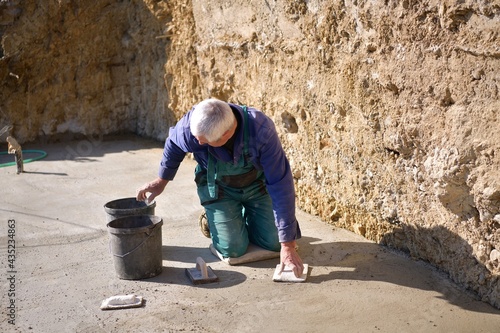 The mason kneels and cleans the concrete floor