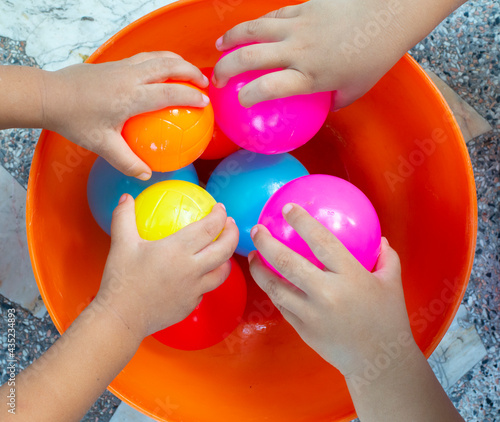 The hands of many children who are playing toys together