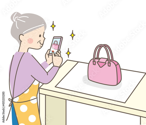 スマートフォンでバッグを撮影するシニア女性