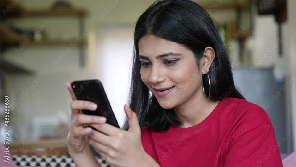 Beautiful Asian woman smiling happily while doing chat reading message on her smart phone at home indoor.lifestyle concept.cheerful Asian girl happily chatting online with friends on smart phone. Beautiful Asian woman smiling happily while doing chat reading message on her smart phone at home indoor.lifestyle concept.cheerful Asian girl happily chatting online with friends on smart phone.